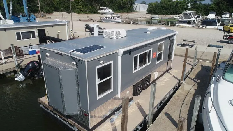 Slide: The Image of 2020 Harbor Home 24' houseboat docked at a marina with solar panels and air conditioning. - 1