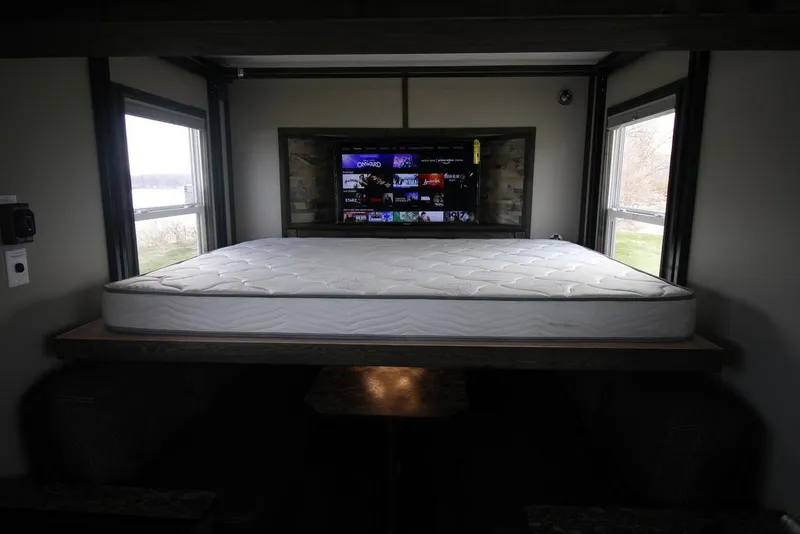 Slide: The Image of 2020 Harbor Home 24' interior with bed and TV, natural light from windows. - 24
