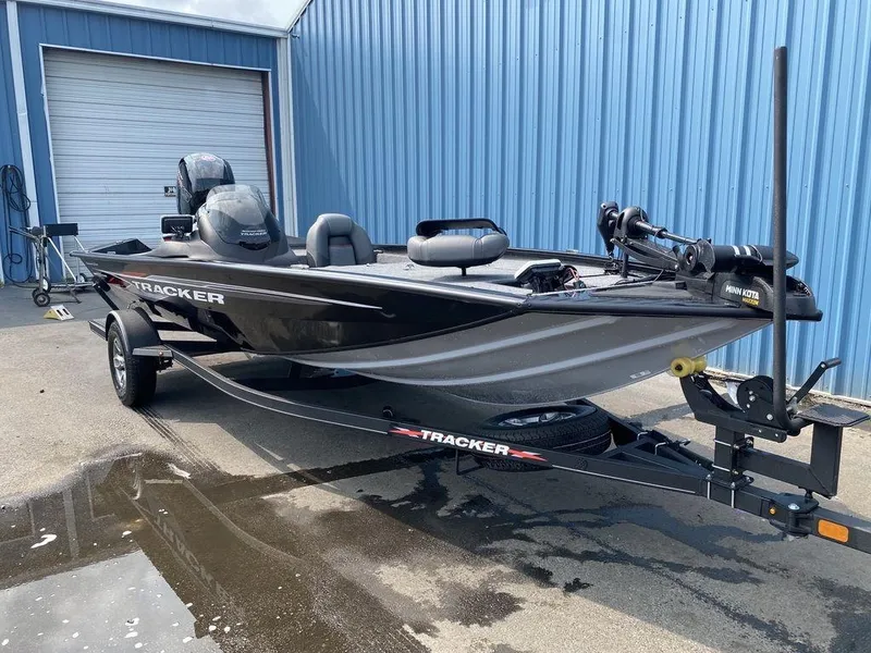 Slide: The Image of 2023 Tracker Pro Team™ 195 TXW fishing boat on trailer, parked outside blue building. - 3