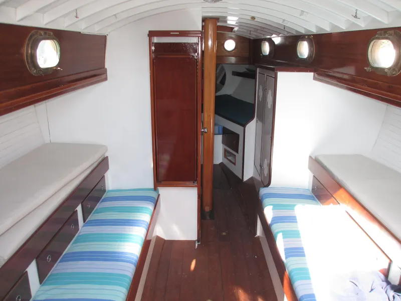 Slide: The Image of Interior of a 1957 Sparkman & Stephens K35 sailboat with wooden furnishings and striped cushions. - 12