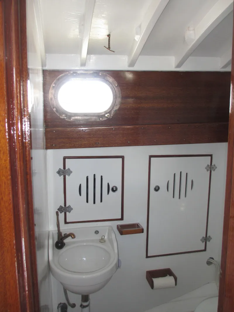 Slide: The Image of 1957 Sparkman & Stephens K35 yacht bathroom with wooden accents and porthole window. - 16