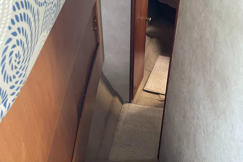 Slide: The Image of Interior hallway of a 1998 Ocean Yachts 40 Sport Fish, featuring carpeted stairs and wooden doors. - 16