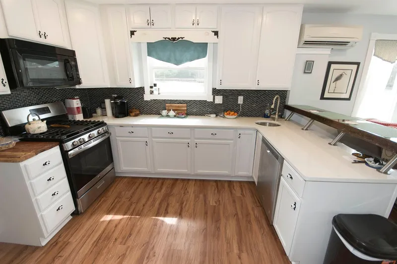 Slide: The Image of Modern kitchen in 2017 Chesapeake 48 Houseboat with white cabinets and wood flooring. - 6