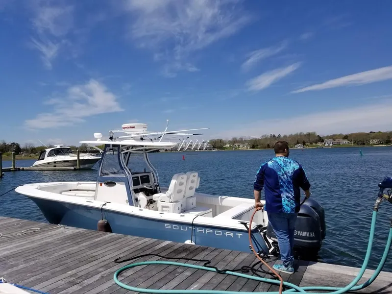 Slide: The Image of 2013 Southport 27 Center Console boat docked, man fueling, clear sky, calm water. - 9