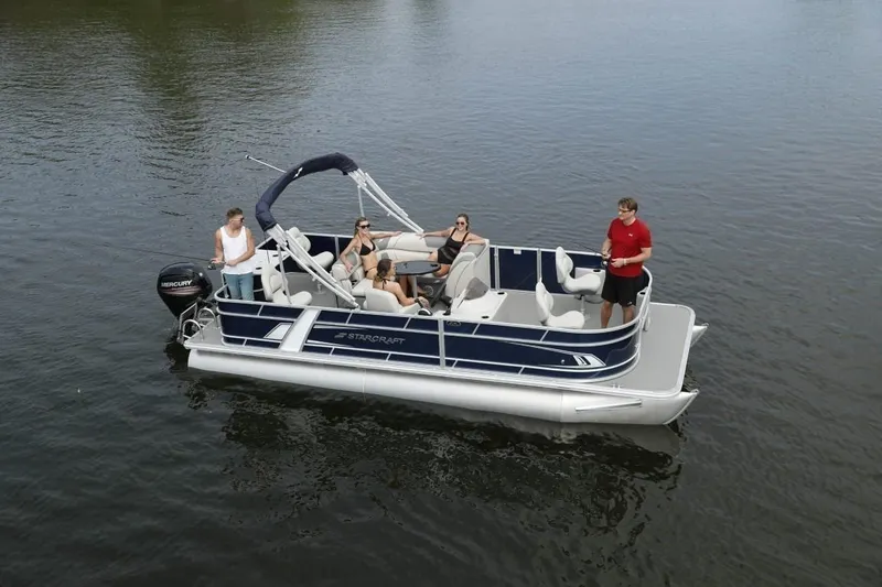 Slide: The Image of 2024 Starcraft 22 LX pontoon boat with passengers on a calm lake. - 2