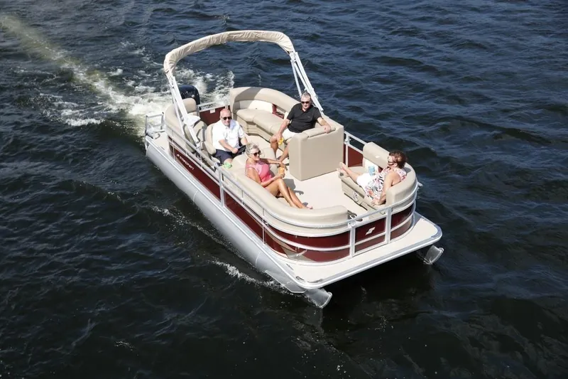 Slide: The Image of 2024 Starcraft LX 18 pontoon boat cruising on a lake with passengers. - 1