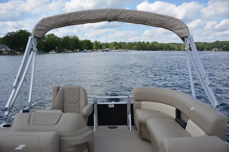 Slide: The Image of 2024 Starcraft LX 16 pontoon boat on a lake with beige seating and canopy. - 4
