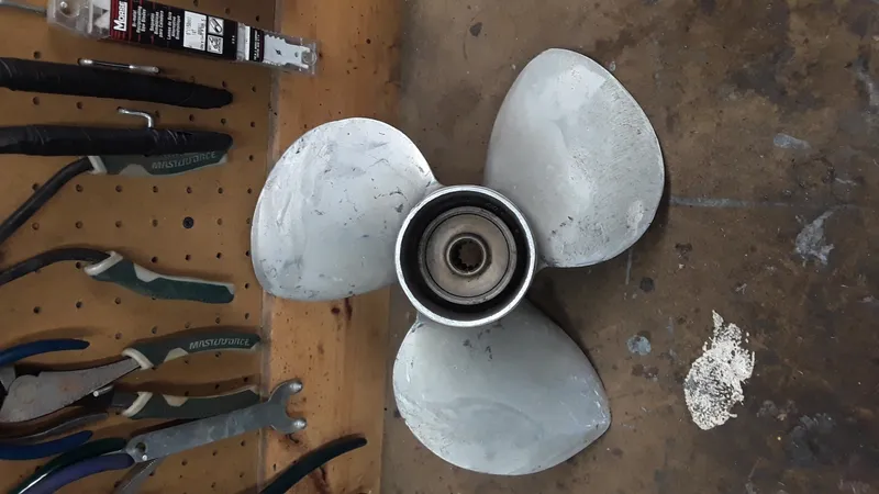 Slide: The Image of 1965 Thompson Sea Lancer boat propeller on a workbench with tools. - 9