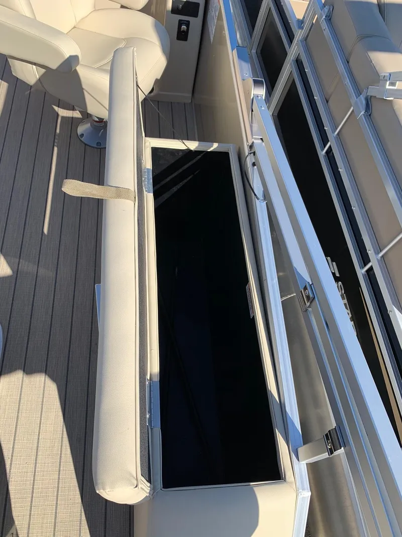 Slide: The Image of 2024 Starcraft EX22Q boat with open storage compartment and beige seating. - 6