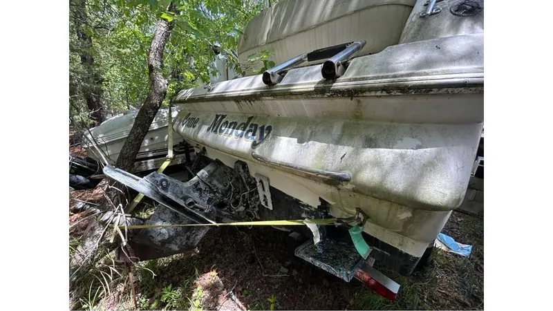 Slide: The Image of 2000 Monterey 242 Cruiser boat, damaged and abandoned in a wooded area. - 6