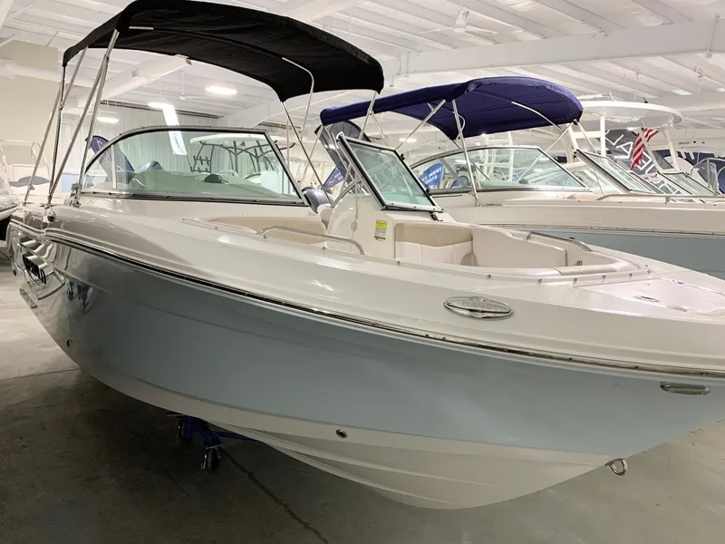 Slide: The Image of 2024 Robalo R207 Dual Console boat in showroom, featuring sleek design and black bimini top. - 3