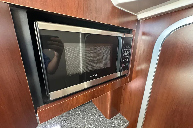 Slide: The Image of Built-in microwave in 2019 Chaparral 347 SSX boat interior with wood paneling. - 23