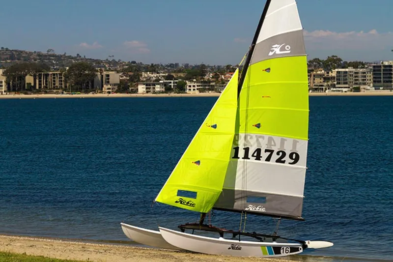 Slide: The Image of 2023 Hobie Cat H16 sailboat with vibrant yellow sails on a beach. - 6