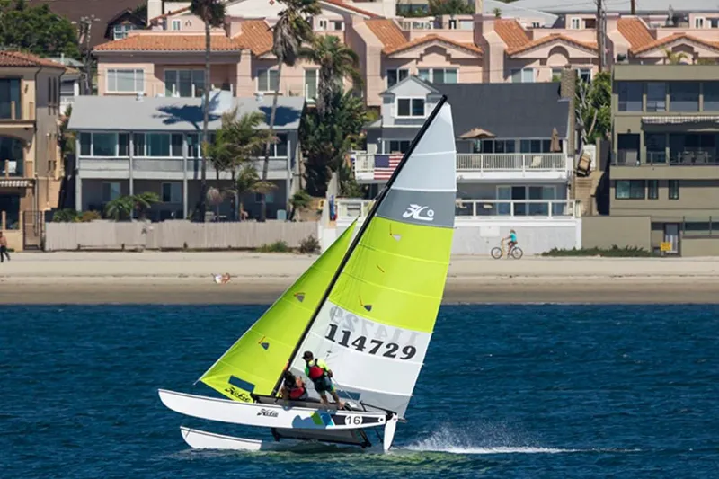 Slide: The Image of 2023 Hobie Cat H16 sailing near a beach with houses in the background. - 7