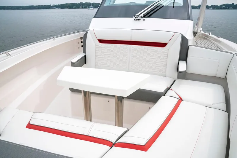 Slide: The Image of 2025 Tiara Sport 34 LS boat interior with white and red seating, table, and lake view. - 23