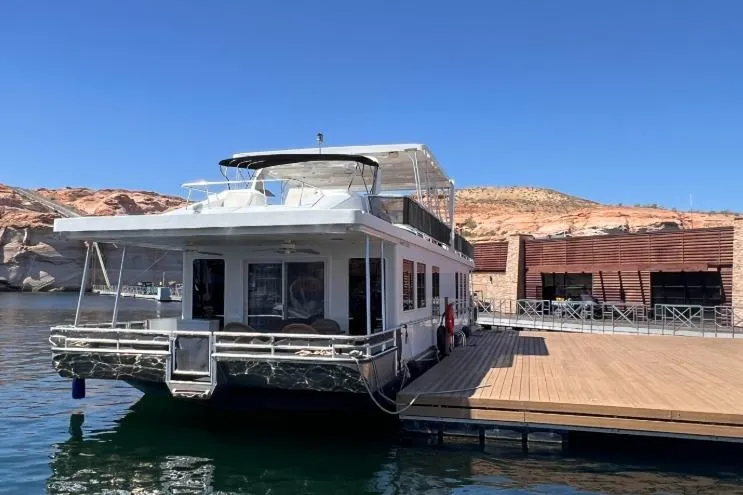 The Image of 2020 Sumerset Antelope Escape Share #4 houseboat docked on a serene lake with rocky backdrop. - 0