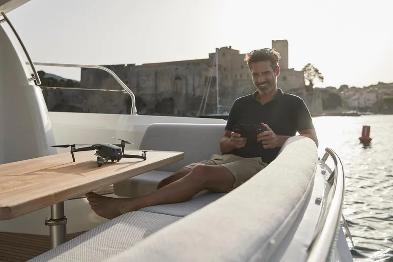 Slide: The Image of Man relaxing on a 2024 Prestige 420 yacht, operating a drone. - 27