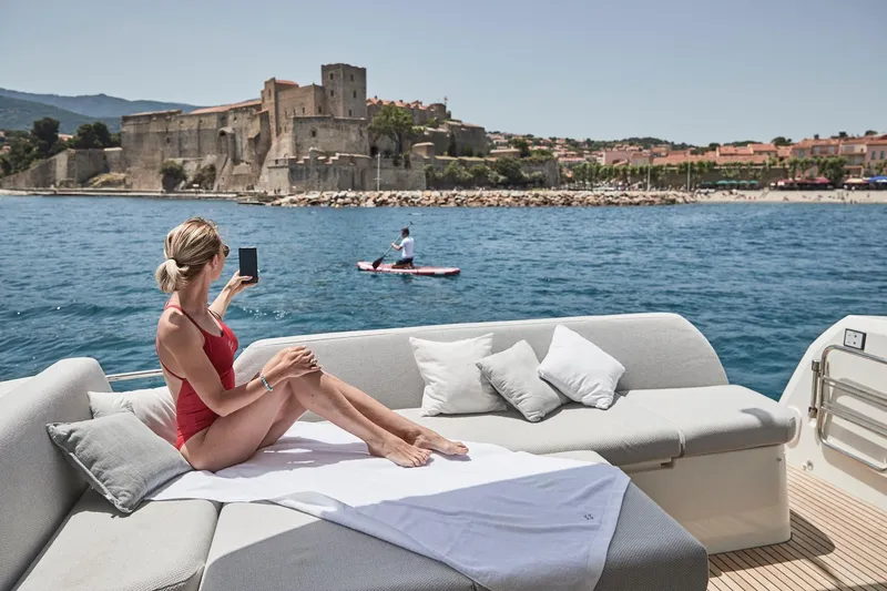 Slide: The Image of Woman relaxing on a 2024 Prestige 420 yacht, with a historic castle in the background. - 29