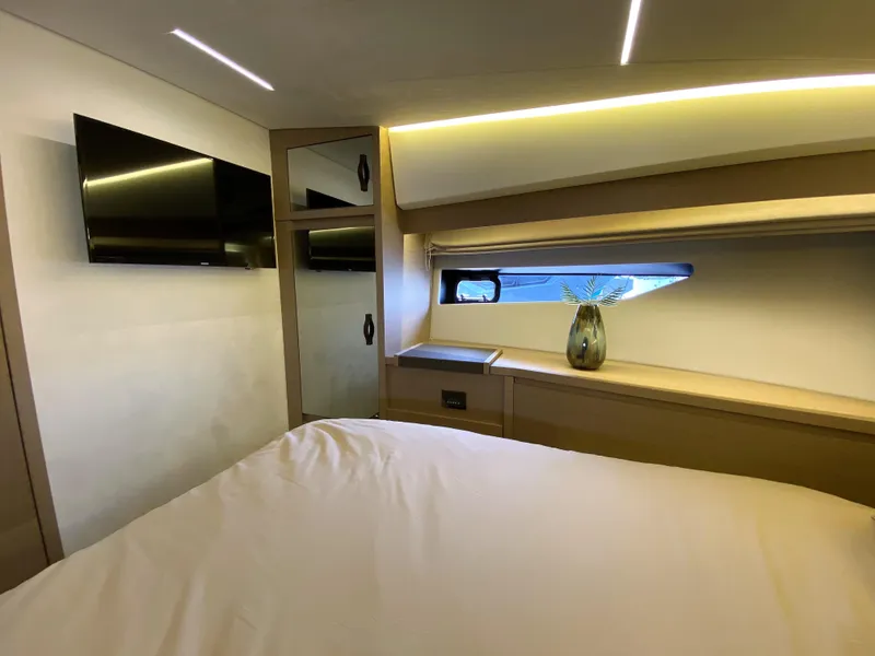 Slide: The Image of Prestige 520 S 2025 yacht bedroom with modern decor, TV, and window view. - 23