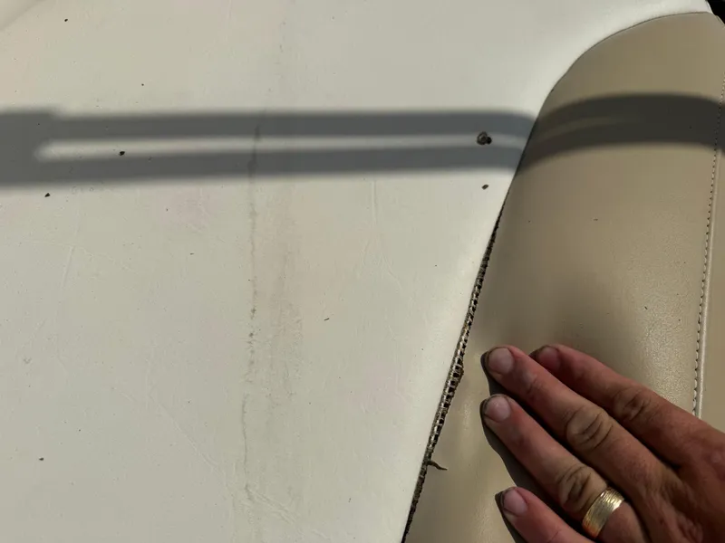 Slide: The Image of Torn upholstery on a 2018 Stingray 191 boat seat with visible hand. - 12