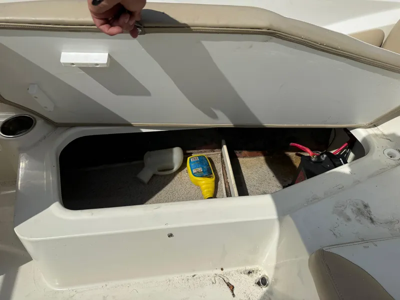 Slide: The Image of Open storage compartment in a 2018 Stingray 191 boat, showing tools and battery. - 15