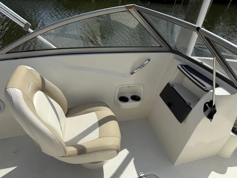 Slide: The Image of 2018 Stingray 191 boat interior with beige seating and dashboard, near water. - 16