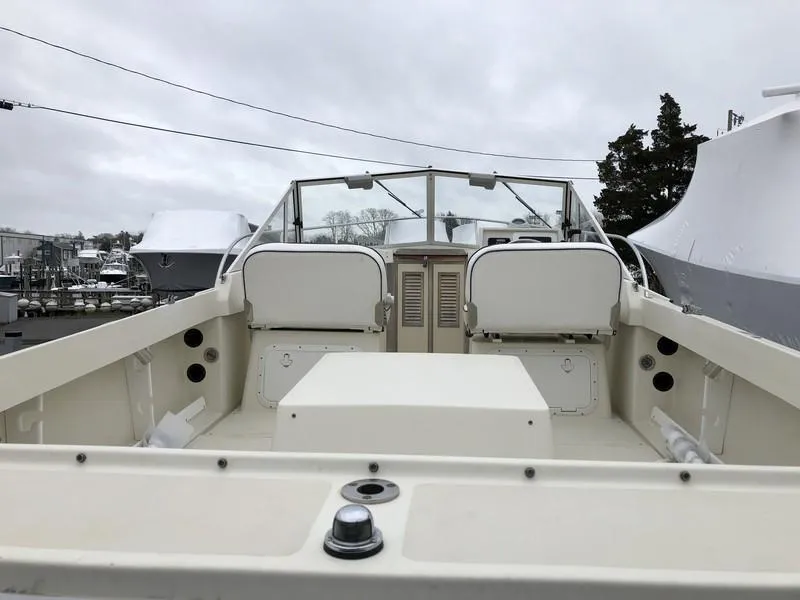 Slide: The Image of 2004 Medeiros Limestone 24 Cuddy Cabin boat, docked, with spacious deck and seating area. - 10