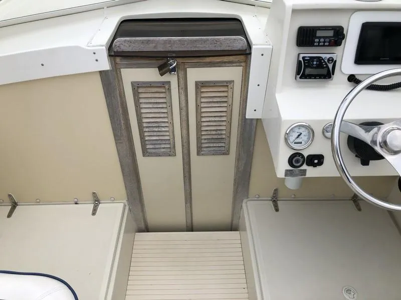 Slide: The Image of 2004 Medeiros Limestone 24 Cuddy Cabin interior with steering wheel, gauges, and cabin door. - 17