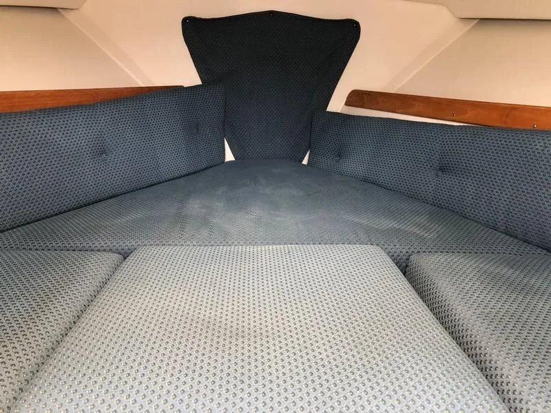 Slide: The Image of 2004 Medeiros Limestone 24 Cuddy Cabin interior with blue cushioned seating and wooden accents. - 23