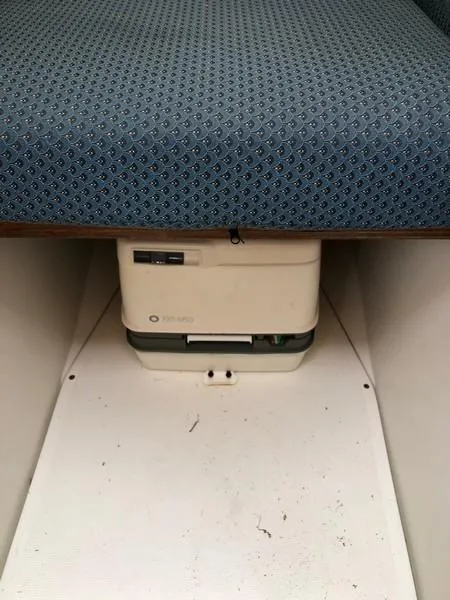 Slide: The Image of 2004 Medeiros Limestone 24 Cuddy Cabin interior with portable toilet under blue cushioned seat. - 27