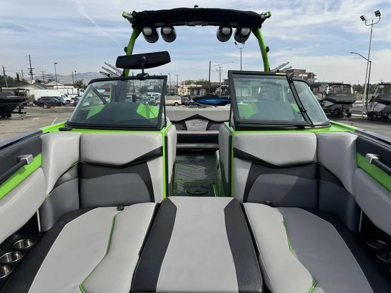 Slide: The Image of 2018 Supra SA450 boat interior with gray and green seating, open windshield, and tower speakers. - 12