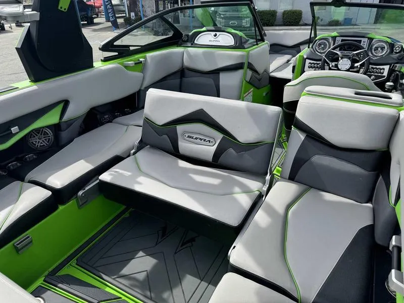 Slide: The Image of 2018 Supra SA450 boat interior with gray and green seating, modern dashboard, and spacious layout. - 13
