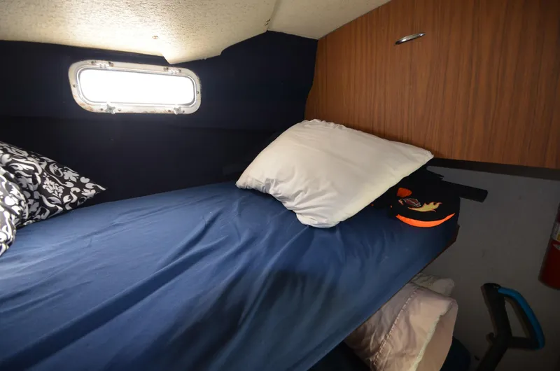 Slide: The Image of Cozy sleeping quarters in a 1975 Bayliner Montego boat with a small window. - 15