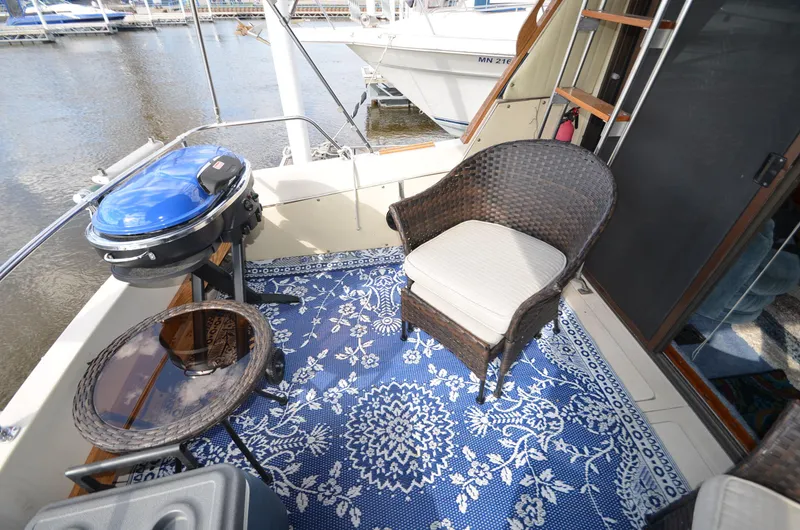 Slide: The Image of 1975 Bayliner Montego boat deck with wicker chair, blue patterned rug, and grill. - 4