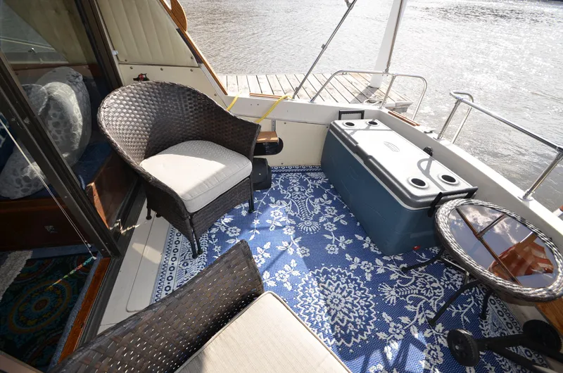 Slide: The Image of 1975 Bayliner Montego boat deck with wicker chairs, cooler, and patterned blue rug. - 5