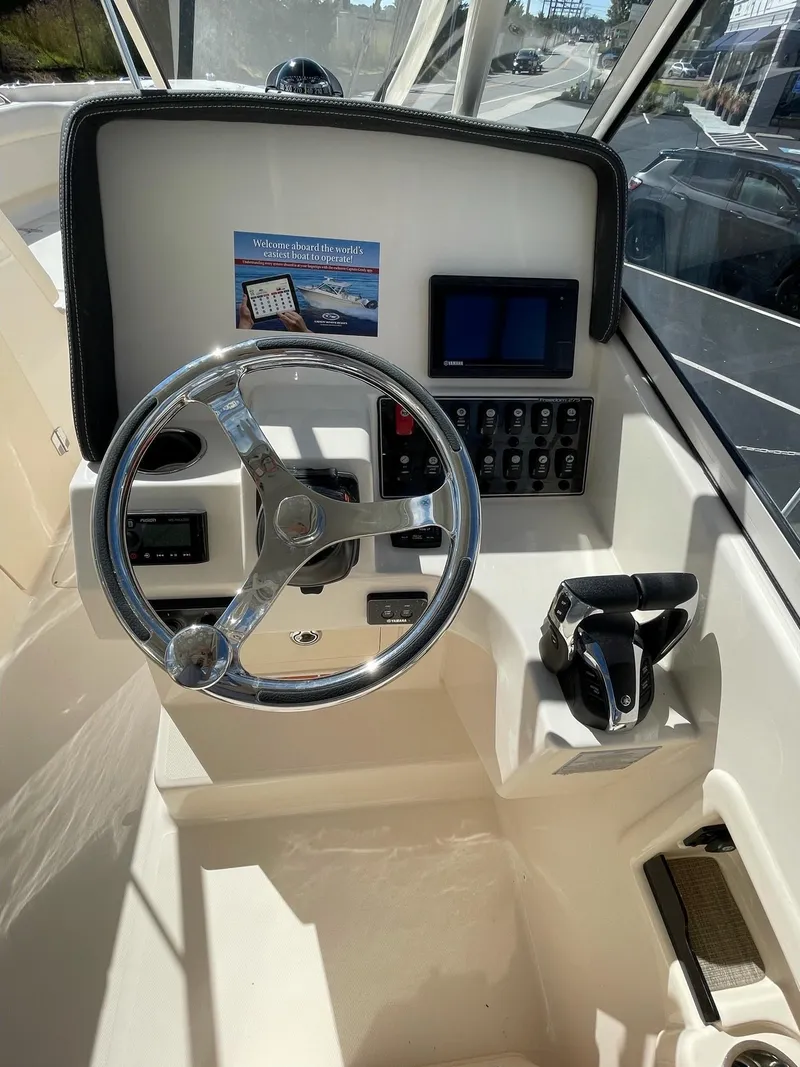 Slide: The Image of 2024 Grady-White Freedom 275 boat helm with steering wheel and control panel. - 3