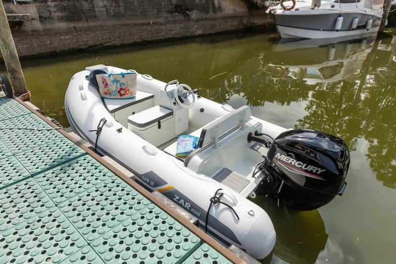Slide: The Image of 2023 ZAR Mini LUX 12 inflatable boat docked with Mercury outboard motor. - 1