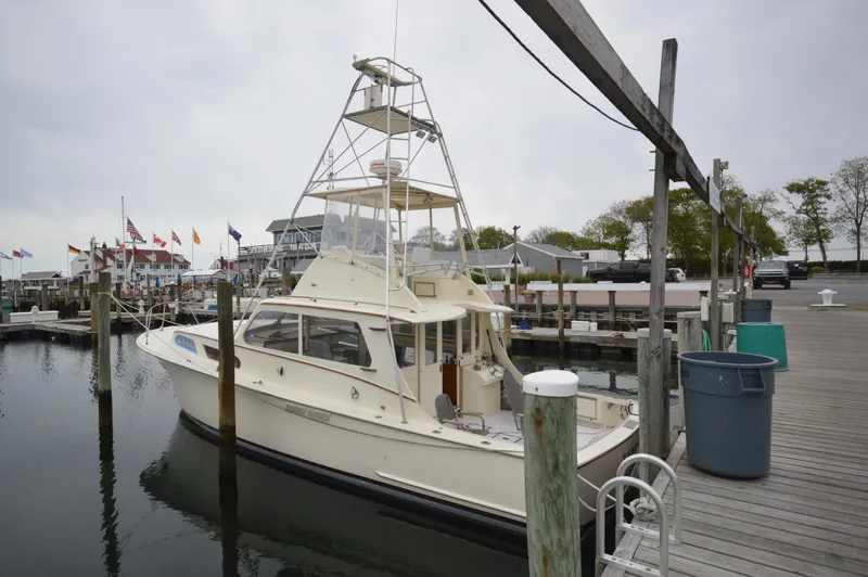 Slide: The Image of 1961 Hatteras 41 Convertible docked at a marina with flags in the background. - 3