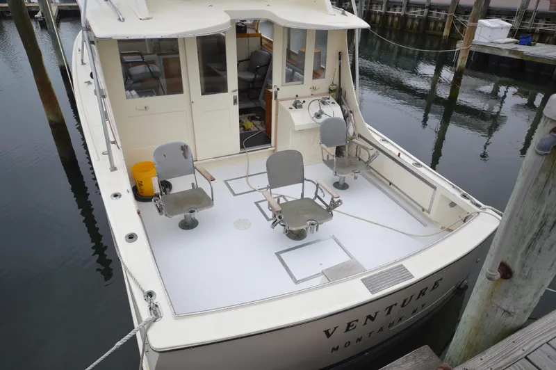 Slide: The Image of 1961 Hatteras 41 Convertible boat docked, rear view with fishing chairs and cockpit. - 5