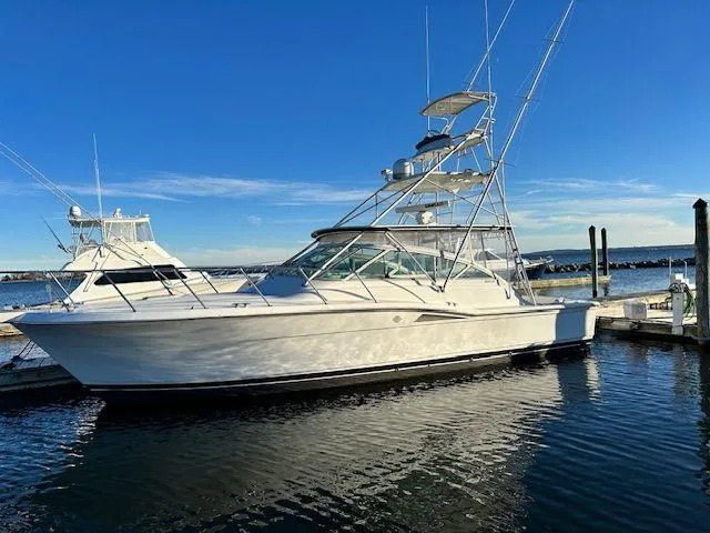 The Image of 1996 Hatteras SPORTFISH EXPRESS yacht docked in a marina under clear blue skies. - 0