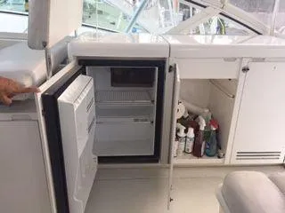 Slide: The Image of 1996 Hatteras SPORTFISH EXPRESS interior with open mini fridge and storage cabinet. - 14