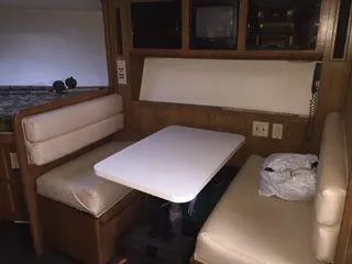 Slide: The Image of 1996 Hatteras SPORTFISH EXPRESS interior with dining area, cushioned seating, and wooden cabinetry. - 15