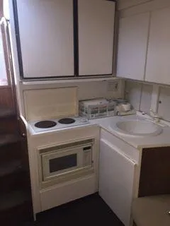 Slide: The Image of Compact kitchen area in a 1996 Hatteras SPORTFISH EXPRESS boat, featuring stove, microwave, and sink. - 21