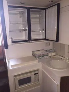 Slide: The Image of 1996 Hatteras SPORTFISH EXPRESS kitchen with microwave, sink, and open cabinets. - 22