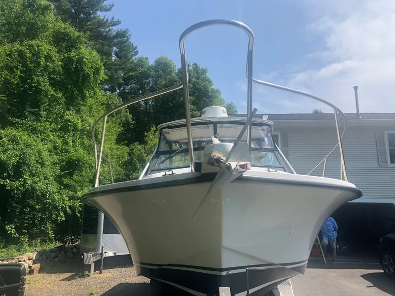 Slide: The Image of 1990 Rampage 24 boat on trailer, parked near house and trees. - 3