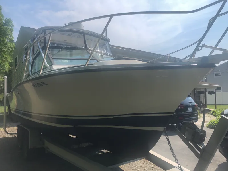 Slide: The Image of 1990 Rampage 24 boat on trailer, parked outdoors under a clear sky. - 4