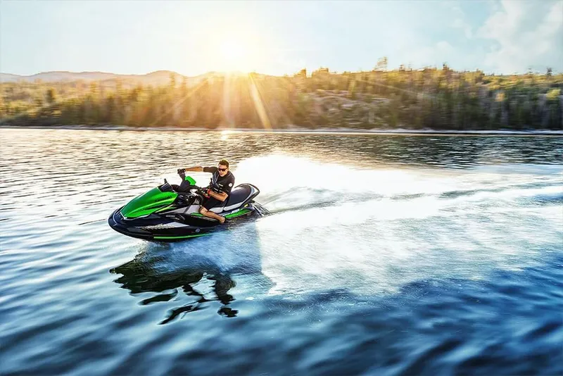 Slide: The Image of 2023 Kawasaki STX 160 jet ski speeding on a lake at sunset. - 13