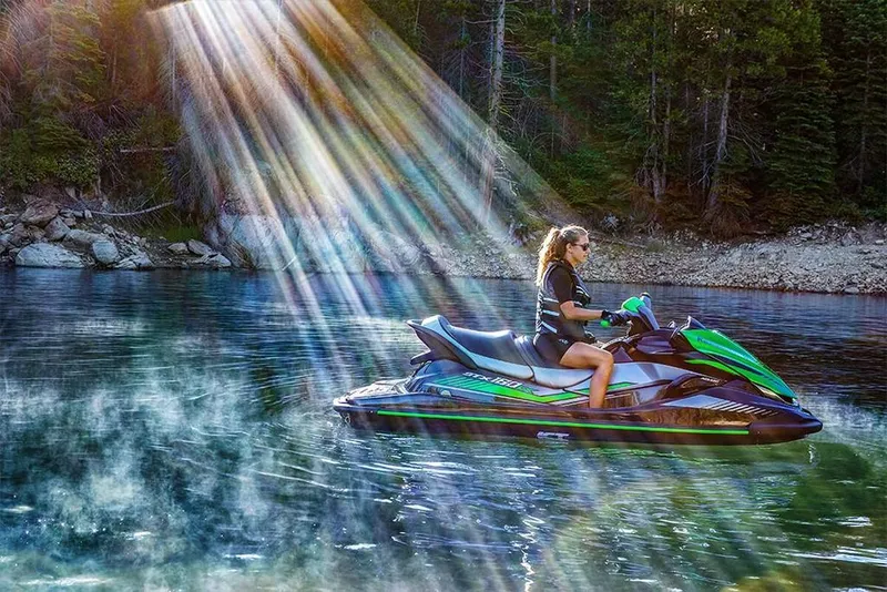 Slide: The Image of 2023 Kawasaki STX 160 jet ski on a serene lake with sun rays. - 17