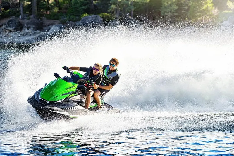 Slide: The Image of 2023 Kawasaki STX 160 jet ski in action on a lake with two riders. - 25