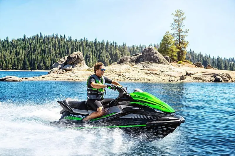 Slide: The Image of Man riding 2023 Kawasaki STX 160 jet ski on a scenic lake. - 27